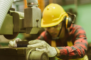 Manufacturer or Metal worker wearing safety glasses and protective helmets using lathe in order to machine or operating drilling machine concentrating on production plant job of production department