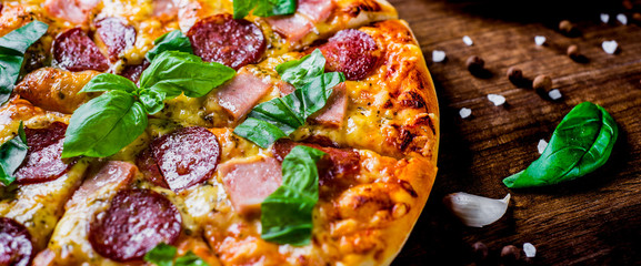 Pepperoni Pizza with Mozzarella cheese, salami, ham, Spices and Fresh basil. Italian pizza on...