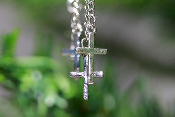 Metal crucifix bracelet hanging on the branches of tree. concept of faith and belief.