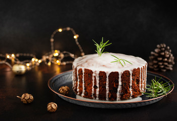 Traditional Christmas cake with fruits and nuts on a dark table and black background. Dessert for the winter holidays. Christmas decorations and lights. Copyspace