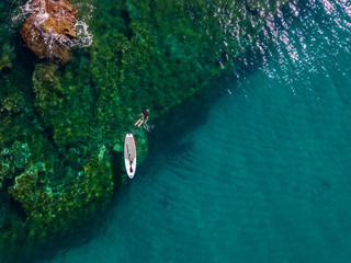 Aerial view of a paddle board in the water floating on a transparent sea, snorkeling. Bathers at sea. Tropea, Calabria, Italy. Diving relaxation and summer vacations. Italian coasts, beaches and rocks