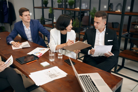 clever woman in stylish white suit giving advise how to earm money, consulting her colleagues at the meeting