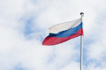 Fototapeta na wymiar The Russian flag flies in the wind against the blue sky.