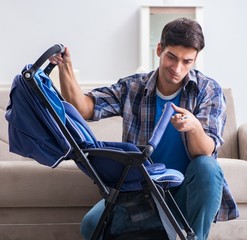 Young father assembling baby pram at home