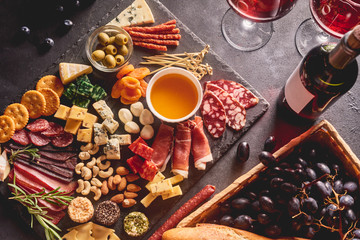 Red wine with different kinds of cheese, charcuterie assortment, crackers, grapes, nuts and berries