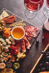 Red wine with different kinds of cheese, charcuterie assortment, crackers, grapes, nuts and berries