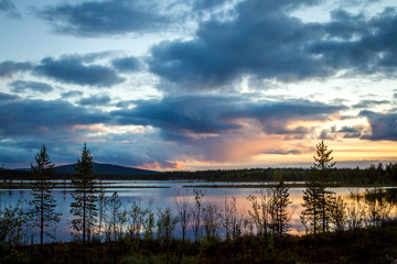 Summer Night landscape in the north of the Kola Peninsula in Russia. White nights, lakes, forests and beautiful clouds reflected in the water
