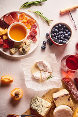 Red wine with different kinds of cheese, charcuterie assortment, crackers, grapes, nuts