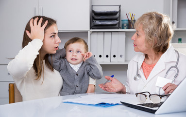 Puzzled woman is listening woman doctor about diagnosis her son