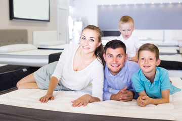  parents with two young sons testing mattress in store