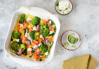 frittata with pumpkin, broccoli and feta cheese on a white plate. light background, top view