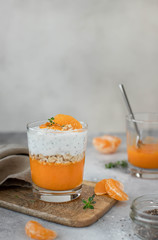 healthy chia pudding with mandarin in a glass. light gray background.
