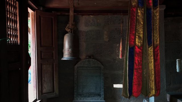Dark room in Bich Dong Pagoda in Vietnam with religious items and a metal bell in the room