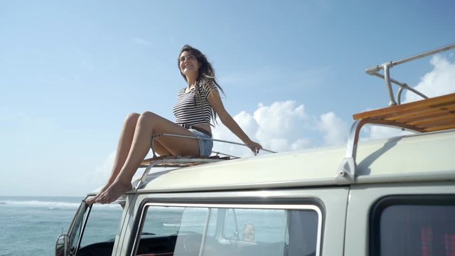 Beautiful woman travel by car and relaxing enjoy road trip nature sitting on the roof at summer day