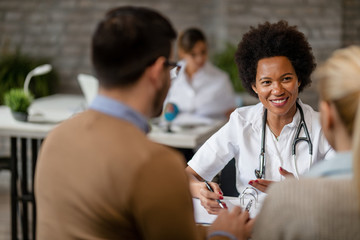 Happy African American doctor having consultations with a couple.