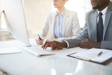 Cropped portrait of African-American businessman typing at keyboard while working on startup project with female colleague, copy space