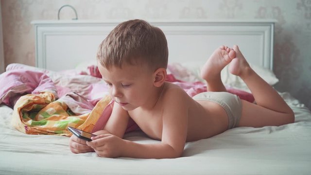 three-year-old boy in bed is using a smartphone.