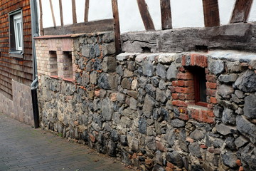 Fachwerkhäuser mit altem Mauerwerk aus Bruchstein und Naturstein im Herbst an der alten Burgruine...
