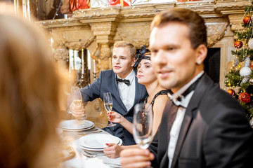 Elegantly dressed people having a festive dinner indoors