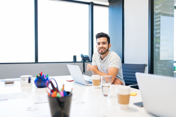 Manger Working Over Laptop At Table In Workplace