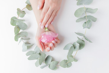 Close-up beautiful sophisticated female hands with pink flowers on white background. Concept care, anti-wrinkles, anti-aging cream, spa
