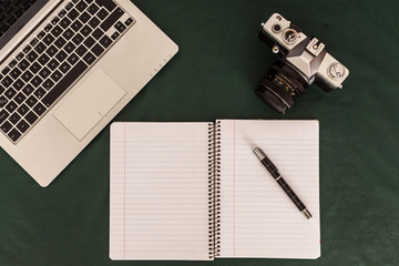 Camara retro , teclado de notebook y cuaderno sobre mantel verde