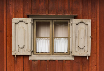 Fototapeta na wymiar Open wooden window on a brown wooden wall in an old house in Sweden.