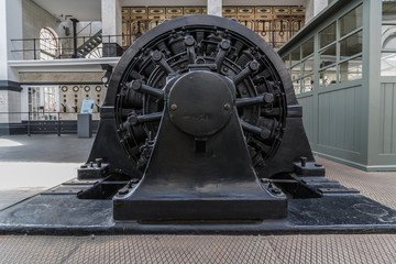 old generator on powerhouse. Side view on black iron electric installation in power plant