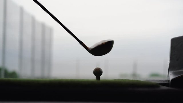 Close-up of golf ball on tee with golf club overlooking driving range at Topgolf