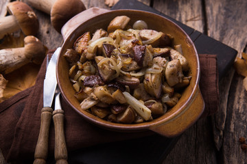Fried forest mushrooms, boletus, onions. Rustic dish in a frying pan, vegetarian autumn food on top of view