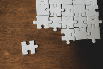 White jigsaw puzzle on brown wood flooring / Business team concept