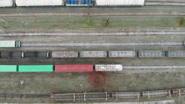Drone top view of cargo freight trains and railway tracks in industrial part of city. Wagons with goods on railroad. 