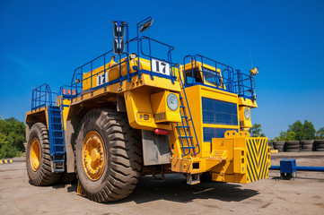 Obraz premium heavy yellow quarry dump truck at repair station at sunny cloudless day