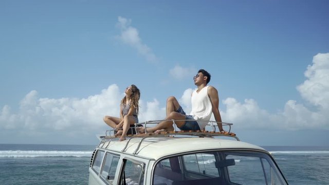 hipster holiday concept. couple with sunglasses sitting on top of minivan roof enjoy sunbeat
