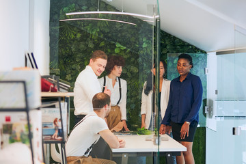 young businesspeople in office boardroom gathered together around white table, discussing their business strategy and sharing information during break. African, asian, caucasian partnership, workteam