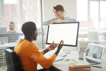 Portrait of smiling young woman talking to African-American man at workplace in office, copy space