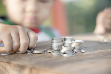 The boy hand holding money coin and stack with layered coin is much more. Business and Finance concept. Money saving concept.