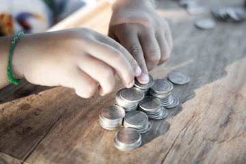 Fototapeta na wymiar The boy hand holding money coin and stack with layered coin is much more. Business and Finance concept. Money saving concept.