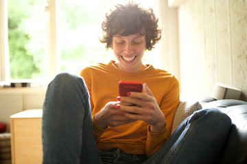 smiling woman sitting at home with mobile phone