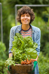 smiling woman holding basket of organic vegetables