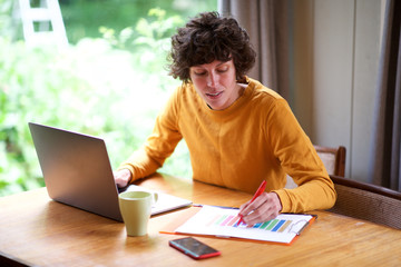 woman working at home with laptop and charts