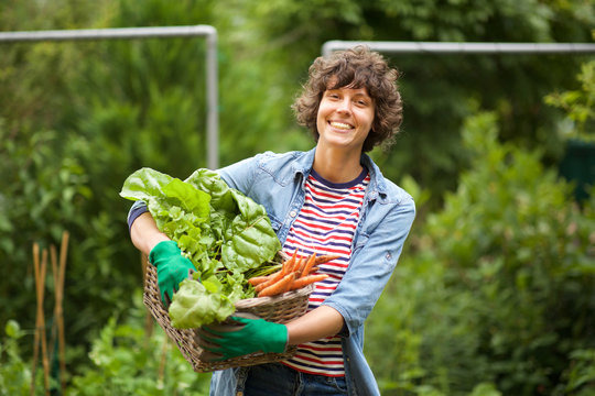 female farmer smiling with bunch of vegetables in basket