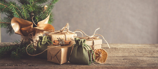 Christmas and zero waste, eco friendly packaging. Woman is wrapping gifts in craft paper on a wooden table, ecological Christmas holiday concept, eco decor