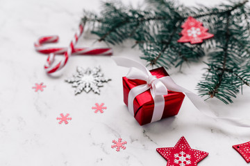  New Year and Christmas card with fir branches, a gift with a ribbon and decor on a marble background. 