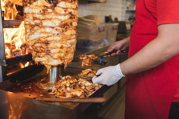 Chef preparing and making Traditional Turkish Doner Kebab meat. Shawarma or gyros. Turkish, greek or middle eastern arab style chicken doner kebab food on isolated white. - obrazy, fototapety, plakaty