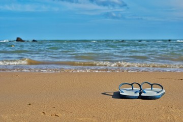 Fototapeta na wymiar Sandals on the beach, sea and sky as the background.