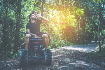 couple driving off road adventure with ATV,UTV bike quad bike on the mountain, man drinking a bottle of water on ATV bike. © Yellow Boat