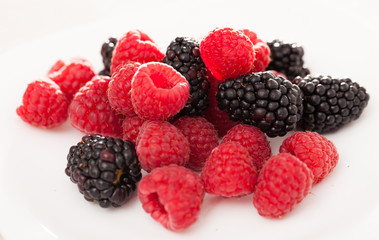 handful of raspberry and blackberry berries on white background