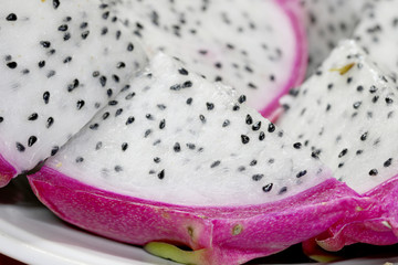 Fototapeta na wymiar Healthy dragon fruit or pitaya pieces background, close up of beautiful fresh sliced dragon fruit with texture in the market in thailand. Pitaya is the plant in Cactaceae family or Cactus.