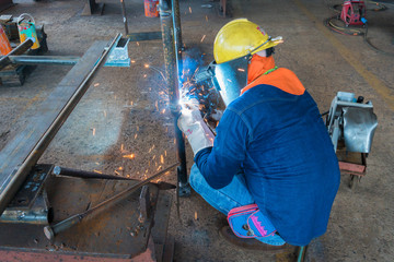Welder is working welding of steel structure by process Flux Cored Arc Welding (FCAW) in Industrial factory.